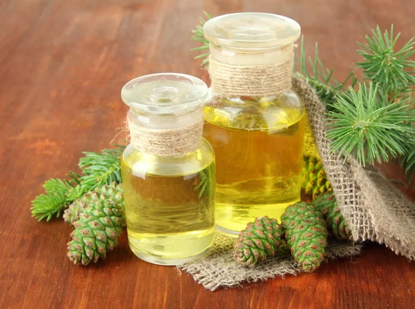 Botellas de aceite de abeto y conos verdes sobre fondo de madera —  Fotos de Stock