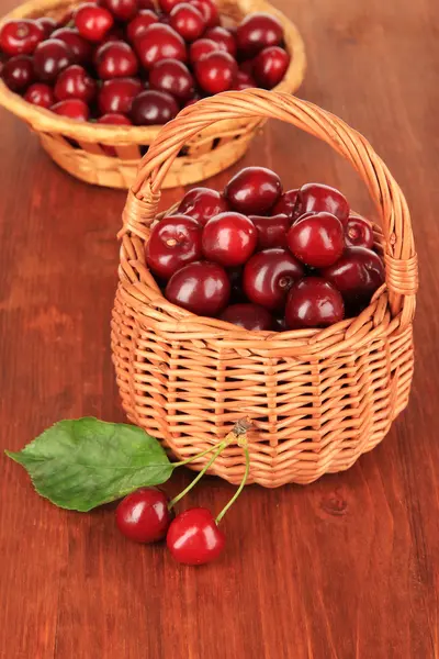 Bacche di ciliegia in cesti di vimini su tavolo di legno primo piano — Foto Stock