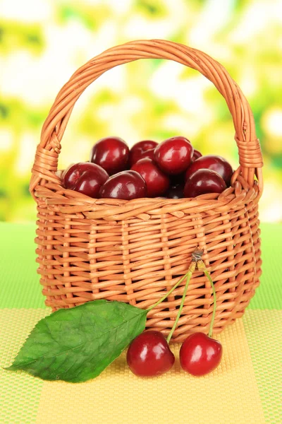 Wiśnia jagody w wiklinowym koszu na stole na jasnym tle — Zdjęcie stockowe