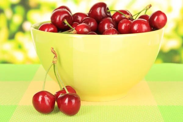 Вишневые ягоды в миске на столе на ярком фоне — стоковое фото
