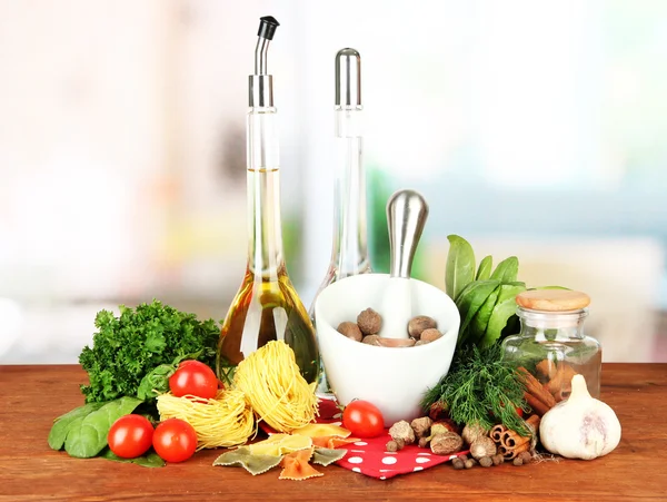 Composition of mortar, pasta and green herbals, on bright background — Stock Photo, Image