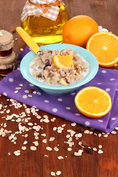 Harina de avena útil en un tazón con fruta en una mesa de madera — Foto de Stock