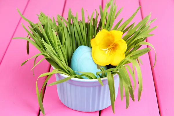 Œuf de Pâques dans un bol avec de l'herbe sur une table en bois rose fermer — Photo