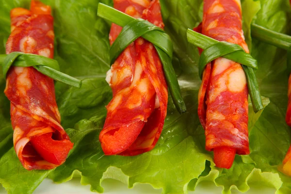 Salami rolls on green salad leaves, close up — Zdjęcie stockowe