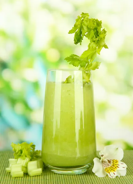 Glass of celery juice, on bamboo mat, on green background — Stock Photo, Image