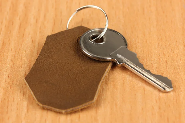 Key with leather trinket on wooden background — Stock Photo, Image