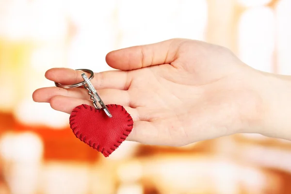 Key with leather trinket in hand on bright background — Stock Photo, Image