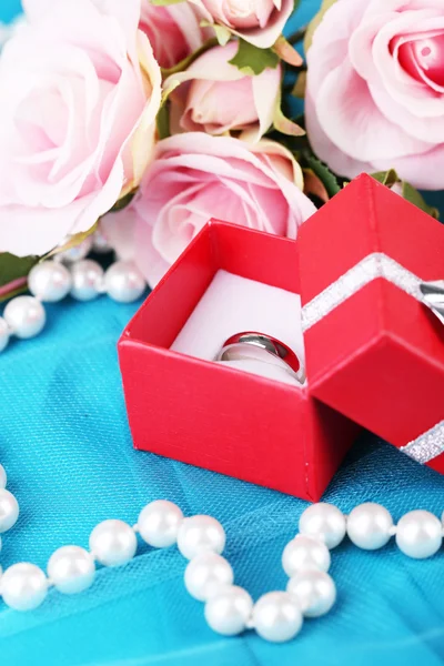 Роза и обручальное кольцо на голубой ткани — стоковое фото