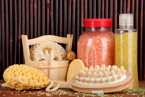 Cleanser, brush and cosmetics for shower on wooden table on bamboo background — Stock Photo, Image