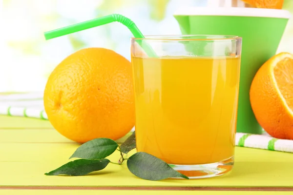 Vaso de jugo, prensa cítrica y naranja madura sobre mesa de madera verde —  Fotos de Stock
