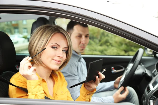 Portrait of young beautiful couple sitting in the car (woman applying makeup) — Stock Photo, Image