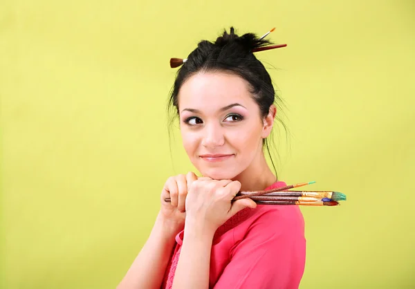 Hermosa joven pintora con pinceles, sobre fondo de color — Foto de Stock