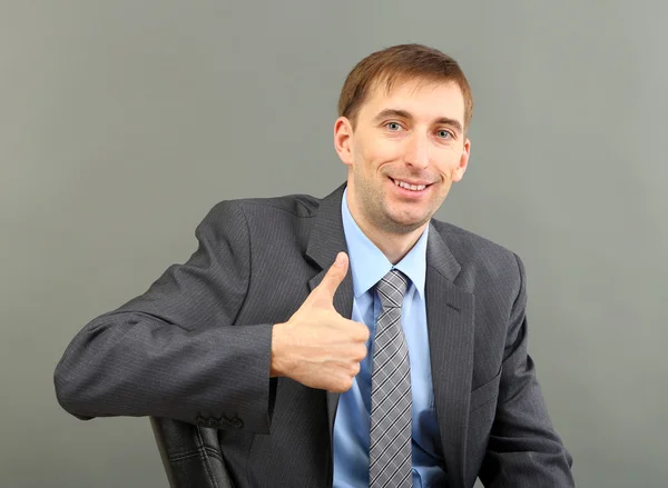 Young businessman on grey background — Stock Photo, Image