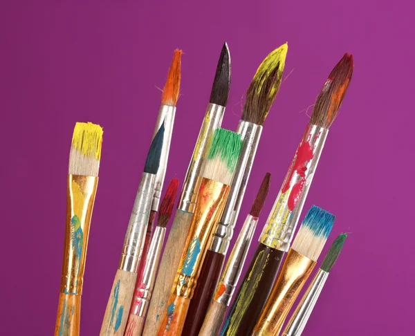 Many brush in paint on purple background — Stock Photo, Image