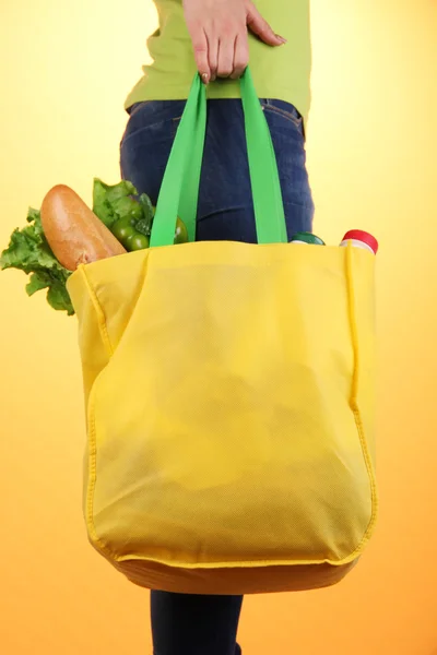 Mädchen mit Einkaufstasche auf orangefarbenem Hintergrund — Stockfoto