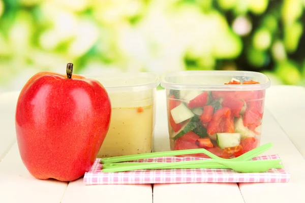 Välsmakande lunch i plastbehållare, på träbord, på ljus bakgrund — Stockfoto