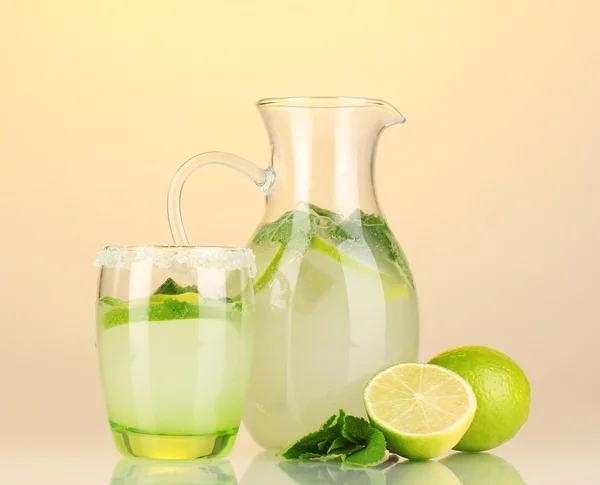 Lemonade in pitcher and glass on yellow background — Stock Photo, Image