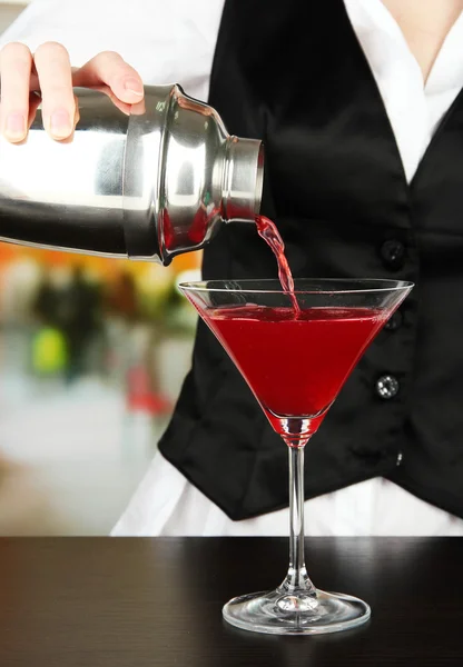 Barmen hand with shaker pouring cocktail into glass, on bright background — Stock Photo, Image