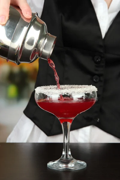 Barmen hand with shaker pouring cocktail into glass, on bright background — Stock Photo, Image