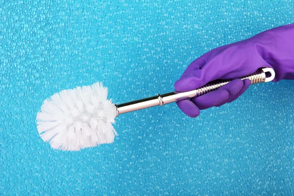 Toilet brush in hand on blue background — Stock Photo, Image