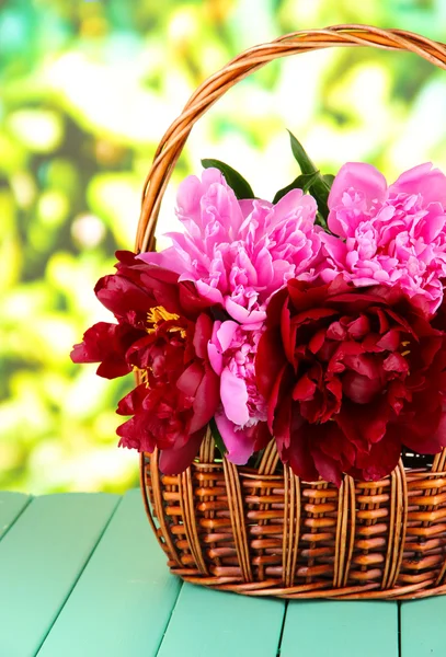 Mooie pioenrozen in rieten mand op tafel op lichte achtergrond — Stockfoto