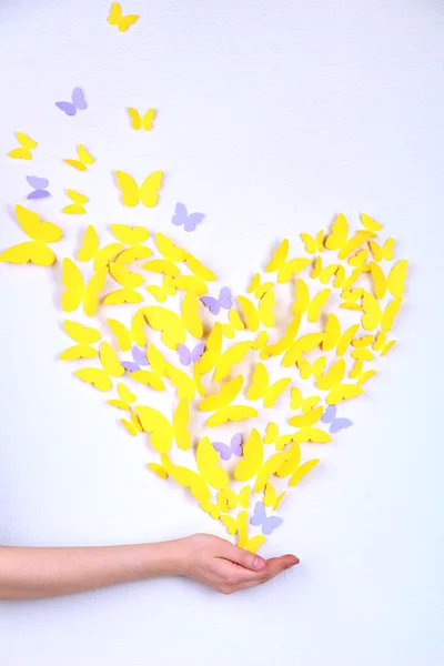 Paperi keltainen perhonen sydämen muodossa seinällä — kuvapankkivalokuva