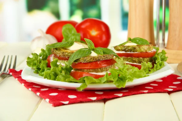 Tasty roasted marrow and tomato slices with salad leaves, on bright background — Stock Photo, Image