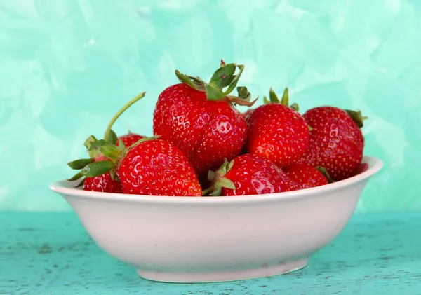 Strawberries in plate on blue background — Stock Photo, Image