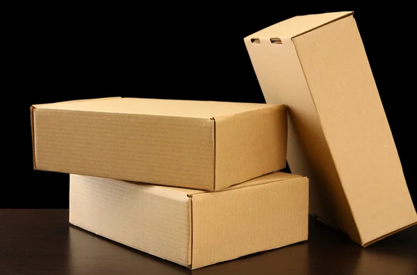 Cajas de paquetes sobre mesa de madera, sobre fondo negro —  Fotos de Stock