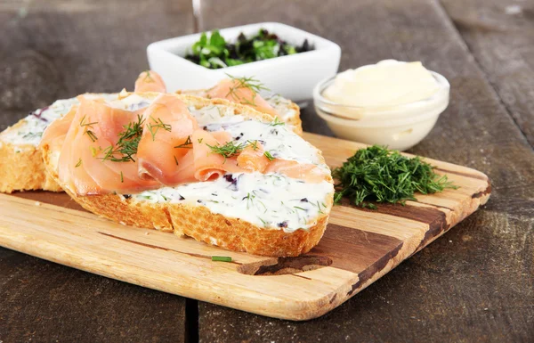 Vis broodjes op snijplank op houten tafel — Stockfoto