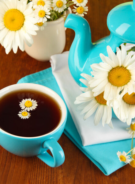 Beautiful bouquet chamomiles in teapot on wooden table close-up