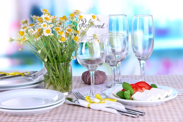 Table setting with chamomiles on checkered tablecloth on window background — Stock Photo, Image