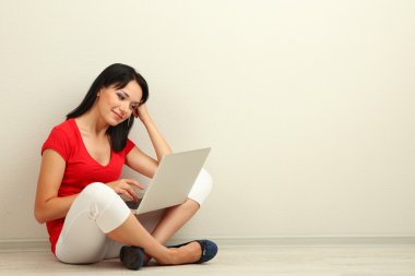 Odada dizüstü bilgisayar ile oturup güzel bir genç kadın