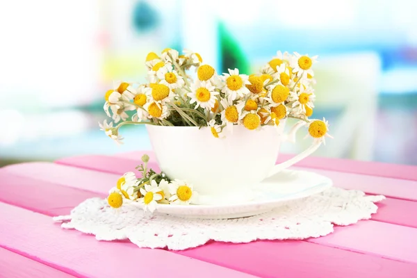 Bouquet de fleurs de camomille en tasse, sur fond lumineux — Photo