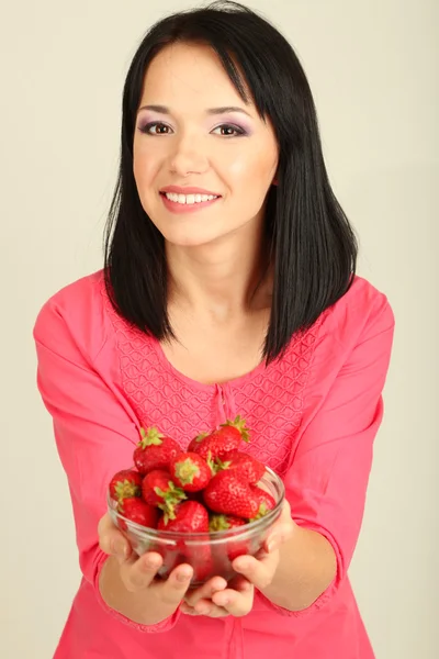 Hermosa joven con fresas sobre fondo gris —  Fotos de Stock