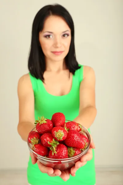 Hermosa joven con fresas sobre fondo gris — Foto de Stock