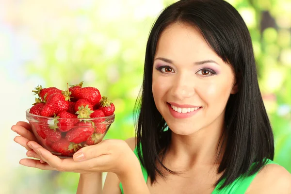 Mooie jonge vrouw met aardbeien op natuurlijke achtergrond — Stockfoto