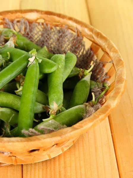 Groene erwten in mand op houten tafel — Stockfoto