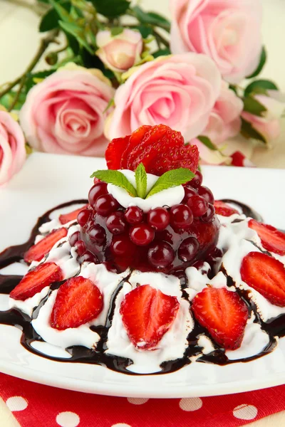 Sabroso postre de gelatina con bayas frescas, sobre fondo de rosas rosadas — Foto de Stock