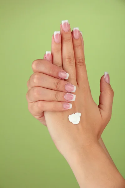 Vrouw met crème op hand, op een achtergrond met kleur — Stockfoto