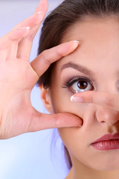 Young woman putting contact lens in her eye close up — Stock Photo, Image