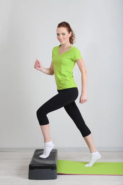 Krásná mladá žena cvičení na krokové — Stock fotografie