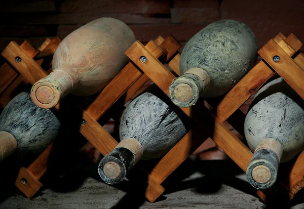 Garrafas velhas de vinho na adega velha, no fundo escuro — Fotografia de Stock