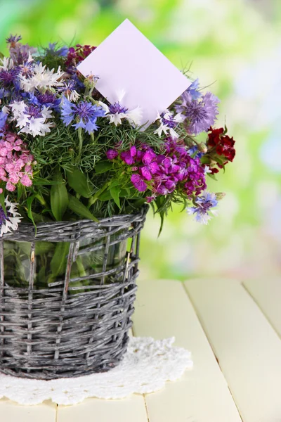 Bellissimo bouquet in cesto su tavolo in legno su sfondo naturale — Foto Stock
