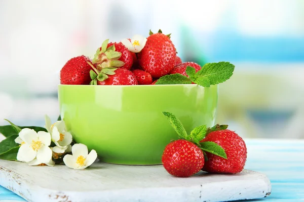 Ripe sweet strawberries in green bowl on blue wooden table — Stock Photo, Image