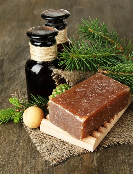 Ručně vyráběné mýdlo a lahve fir tree olej na dřevěné pozadí — Stock fotografie