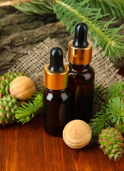 Botellas de aceite de abeto y conos verdes sobre mesa de madera —  Fotos de Stock