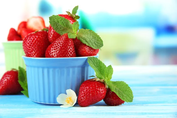 Zralé sladké jahody v miskách na modré dřevěný stůl — Stock fotografie