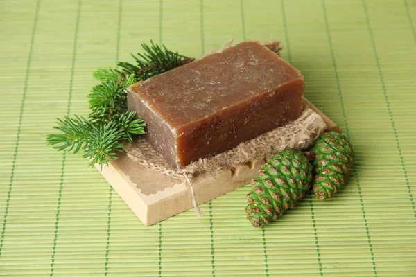 Hand-made soap and green pine cones on bamboo mat — Stock Photo, Image