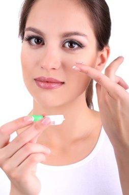 Young woman putting contact lens in her eye close up clipart